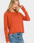 Woman wearing an orange sweater and blue jeans on a white background