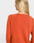 Person wearing a rust-colored sweater on a light gray background