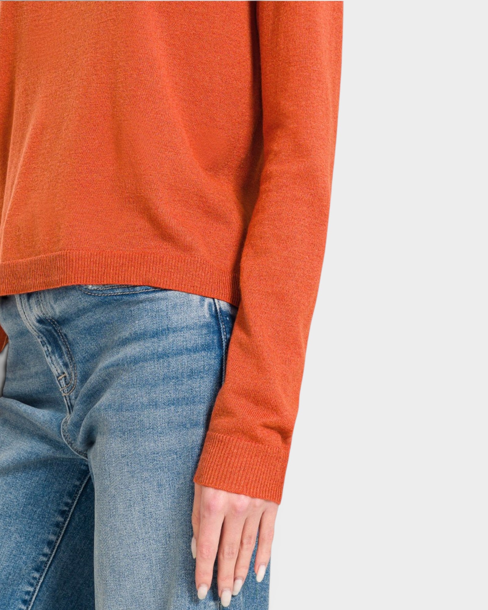 Orange sweater and blue jeans on a neutral background