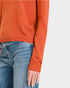 Orange sweater and blue jeans on a neutral background