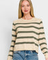 Woman wearing a beige and green striped sweater with blue jeans on a white background