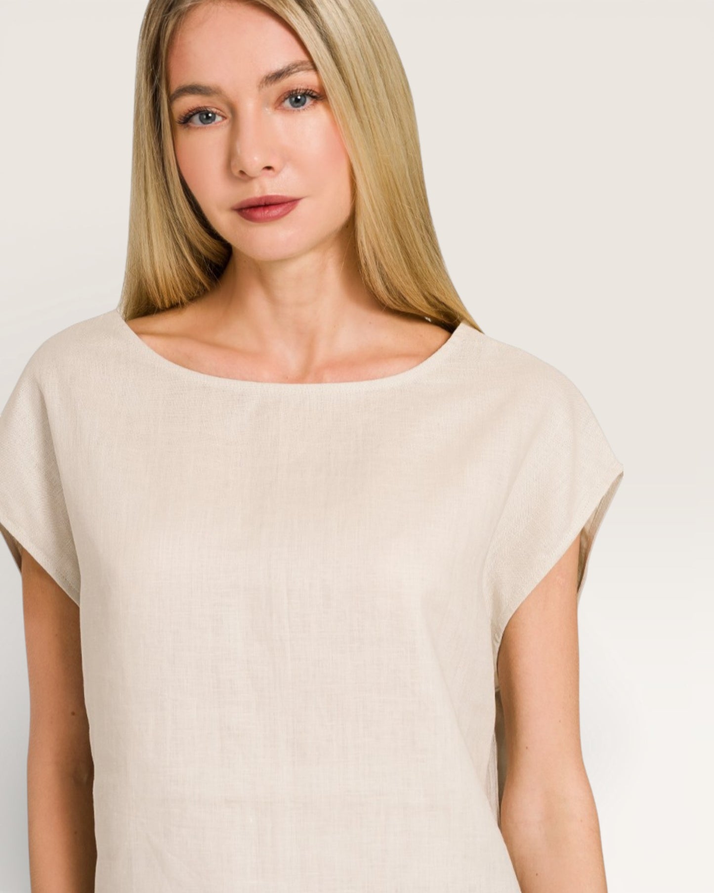 Woman wearing a beige top against a plain background