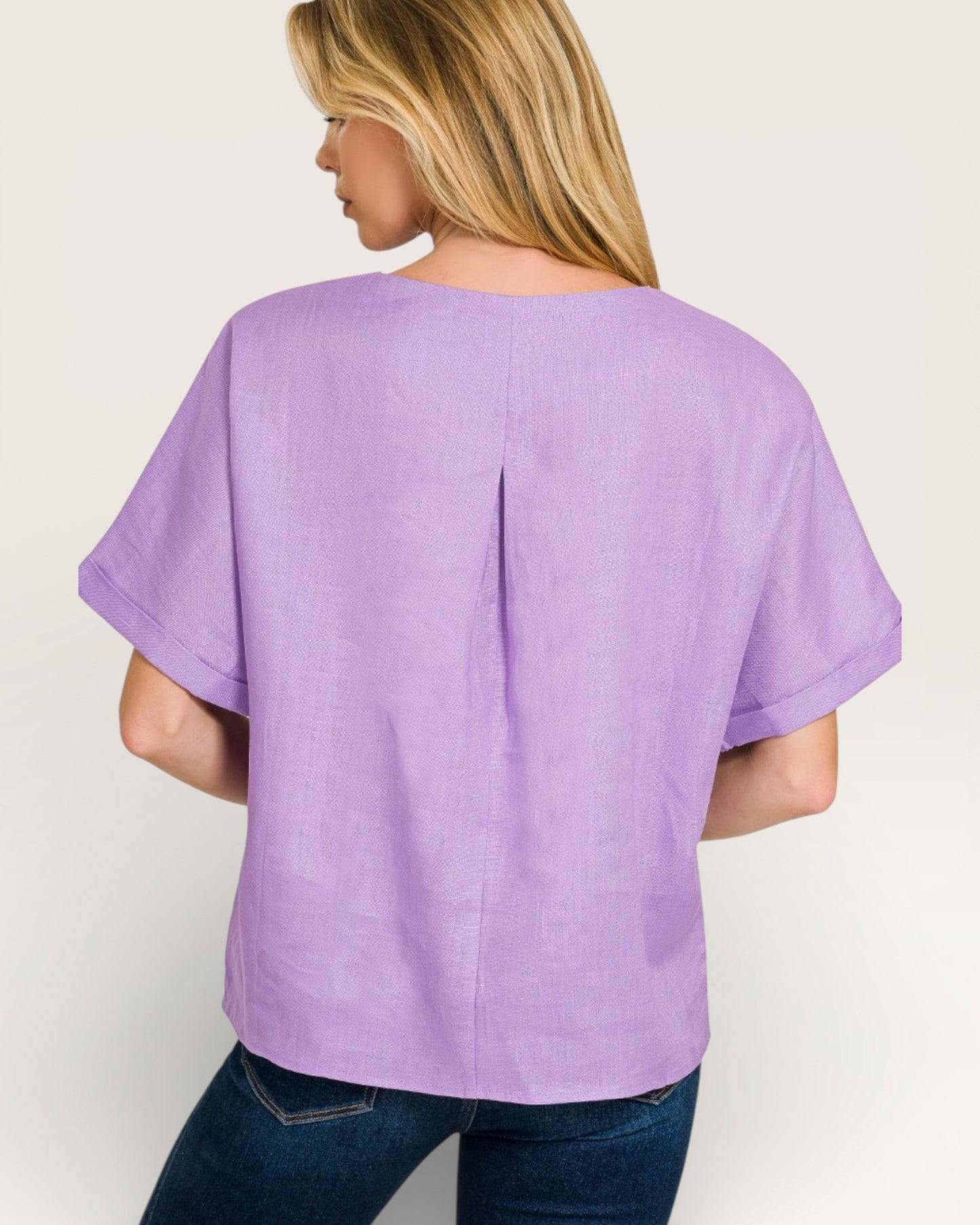 Person wearing a purple top and blue jeans on a plain background