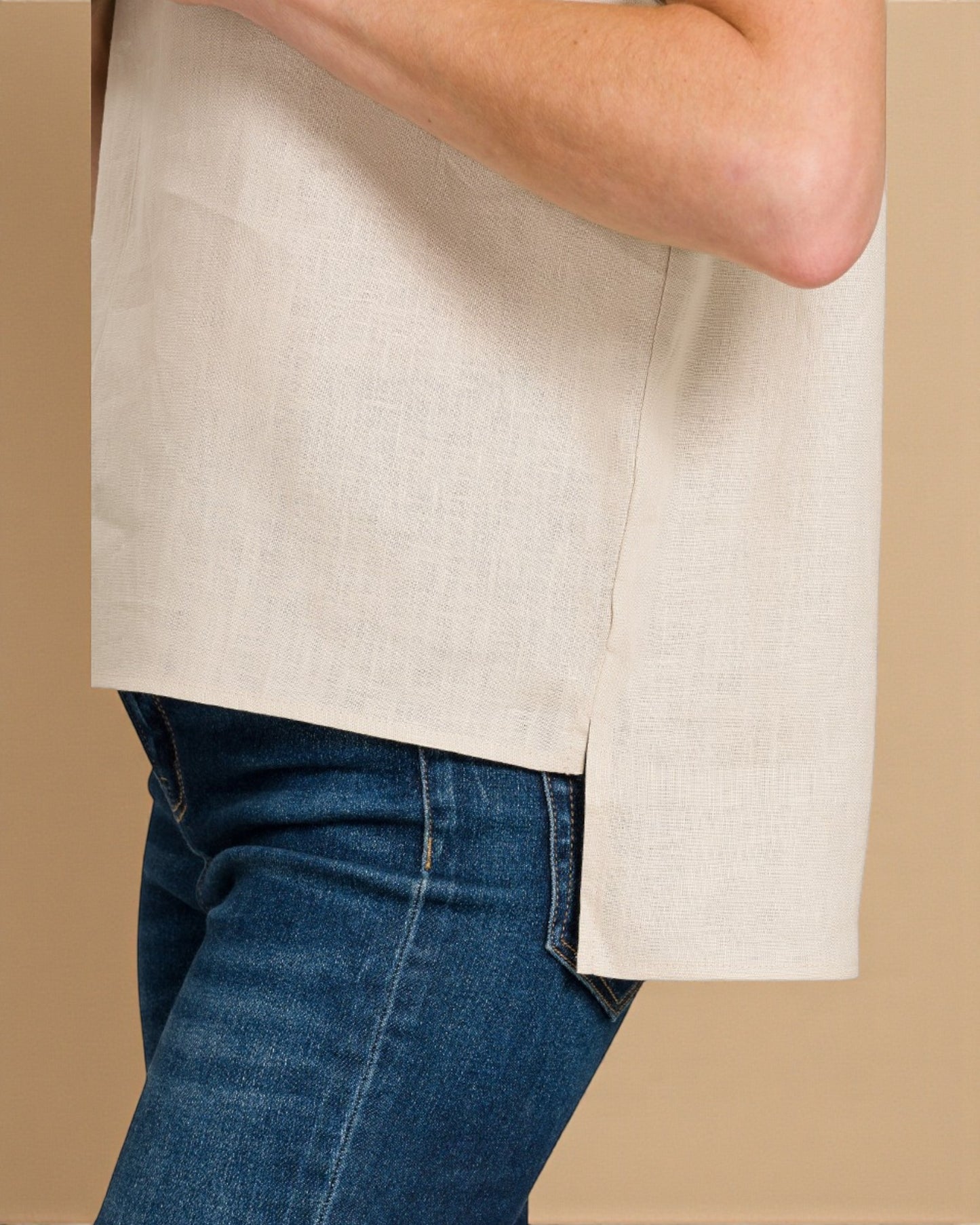 Person wearing a beige shirt and blue jeans on a beige background
