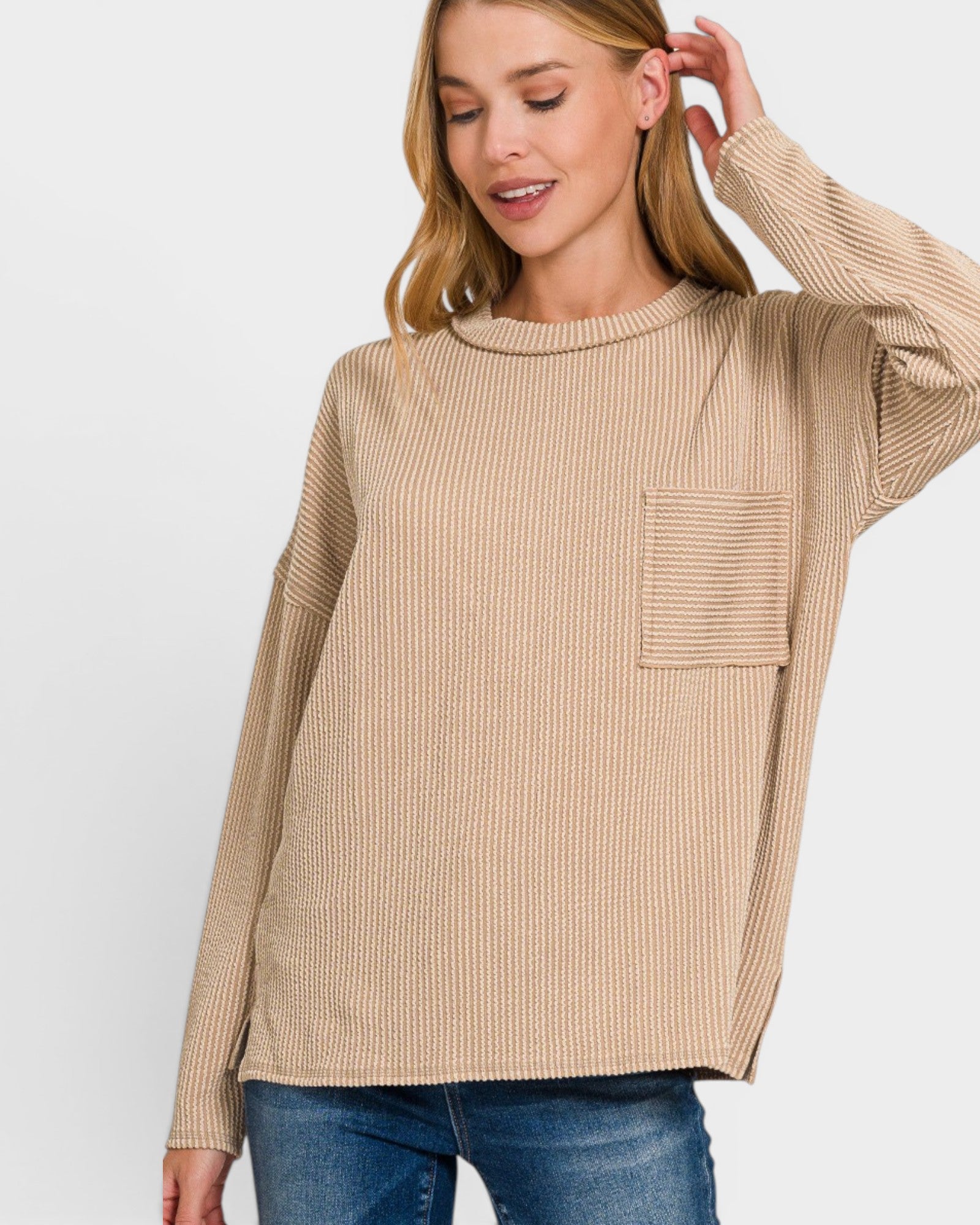 Woman wearing a beige ribbed sweater with a pocket on a white background