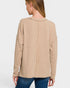 Woman wearing a beige ribbed sweater on a white background