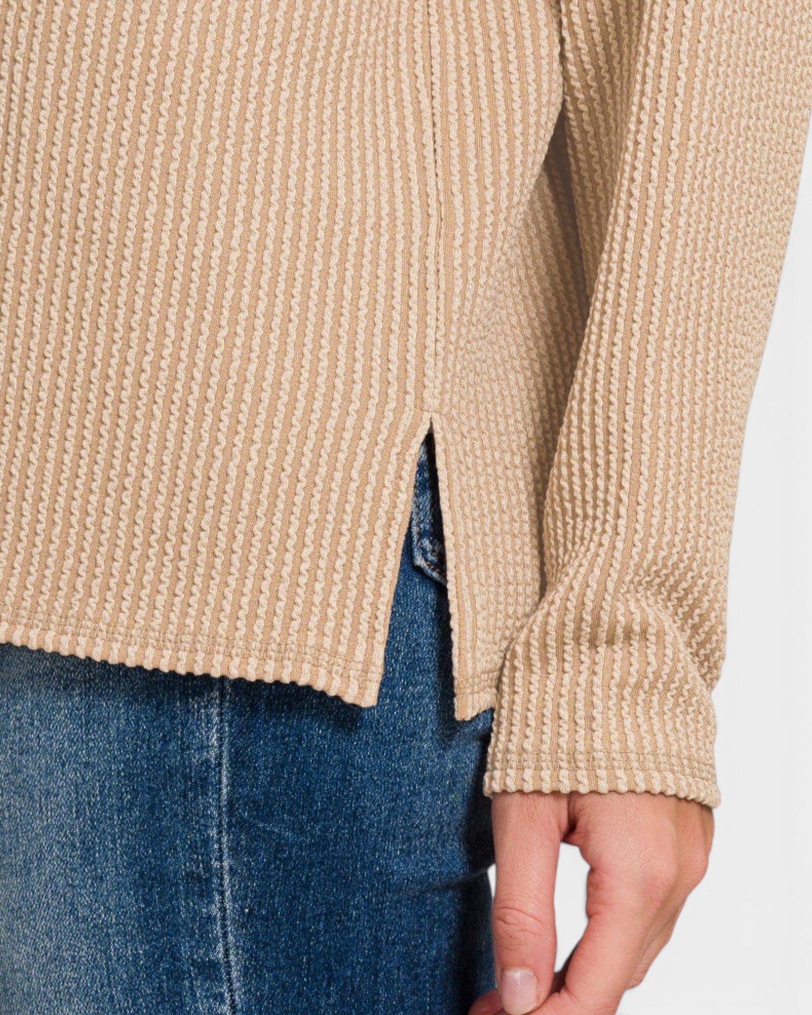 Beige knitted sweater and blue jeans on a neutral background