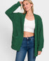 Woman wearing a green cardigan over a white top and blue jeans on a white background