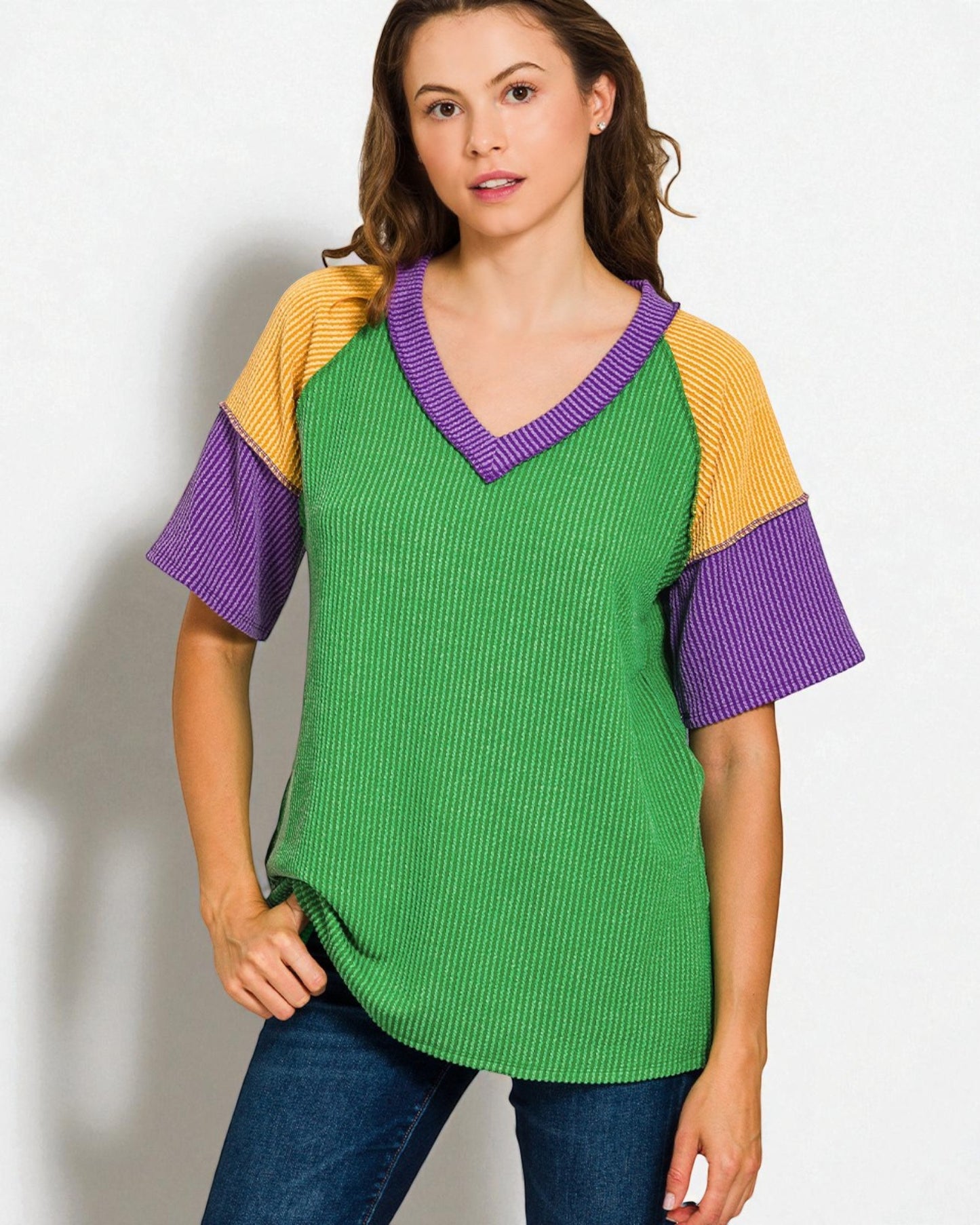 Woman wearing a green sweater with purple and yellow sleeves on a white background