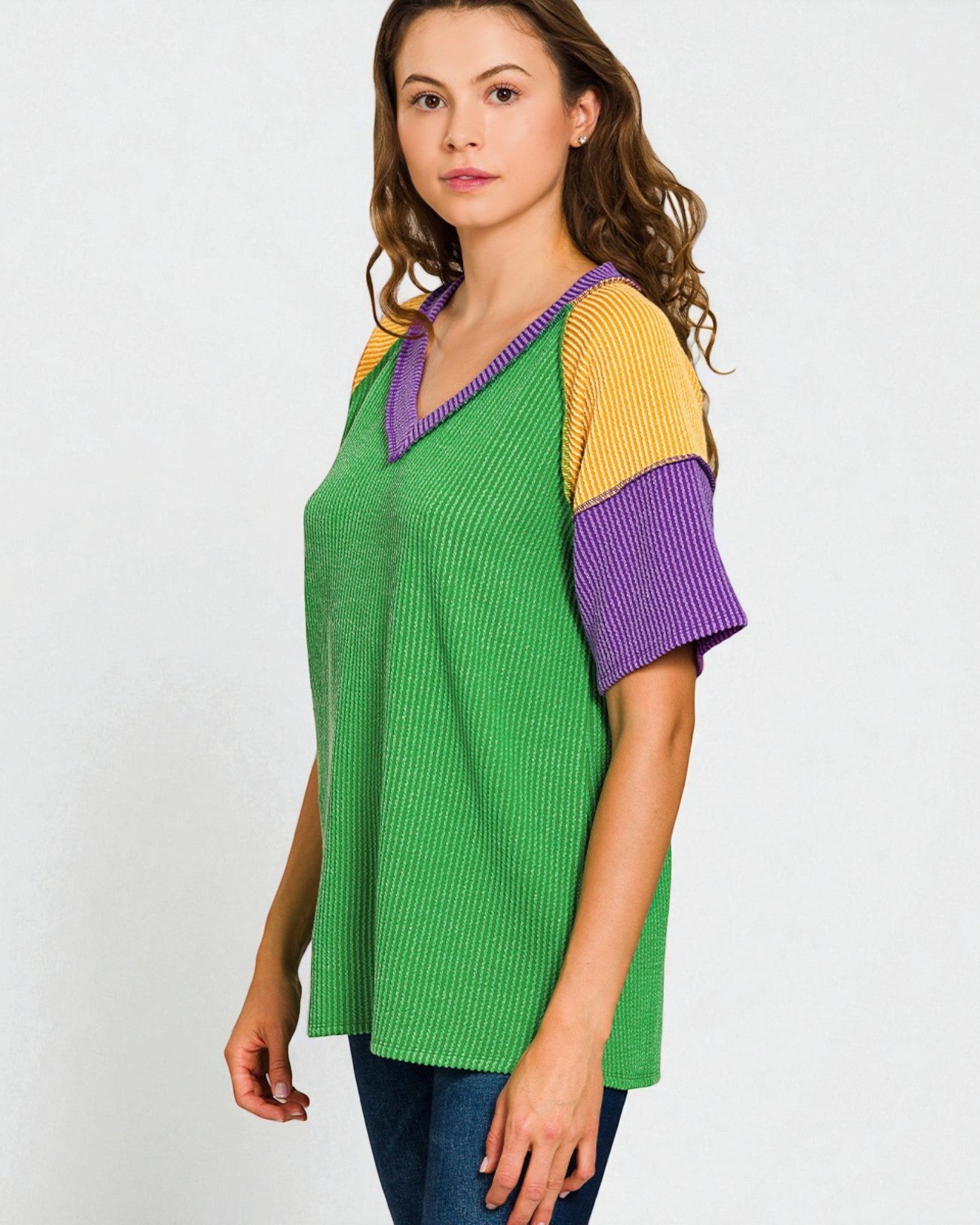 Woman wearing a green, yellow, and purple color-blocked top on a white background