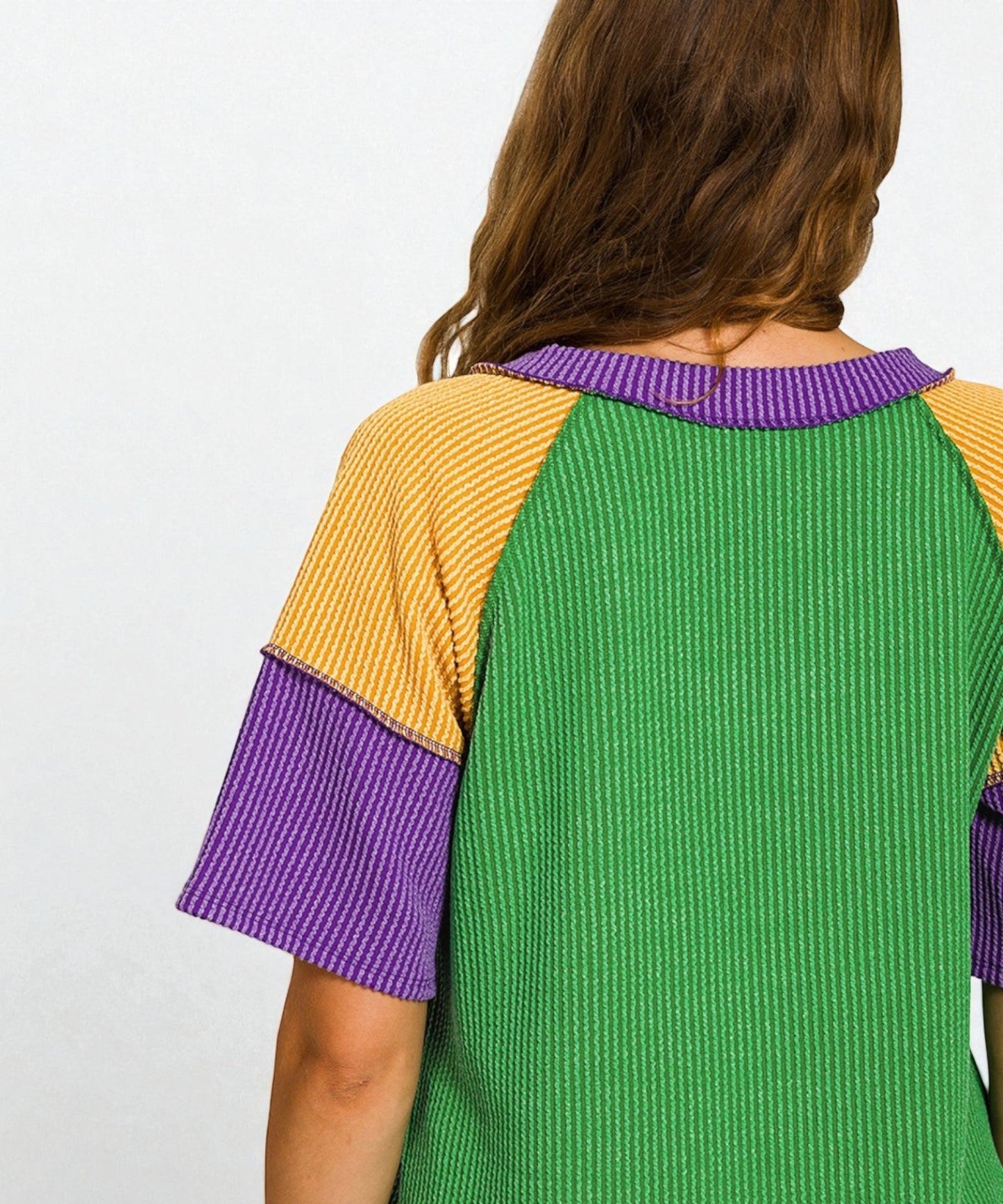 Green dress with yellow sleeves and purple accents on a plain background