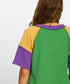 Green dress with yellow sleeves and purple accents on a plain background