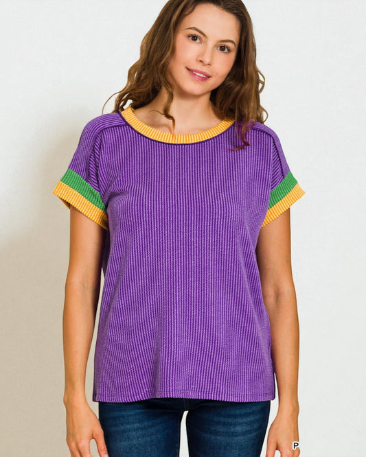 Woman wearing a purple top with colorful sleeves on a plain background