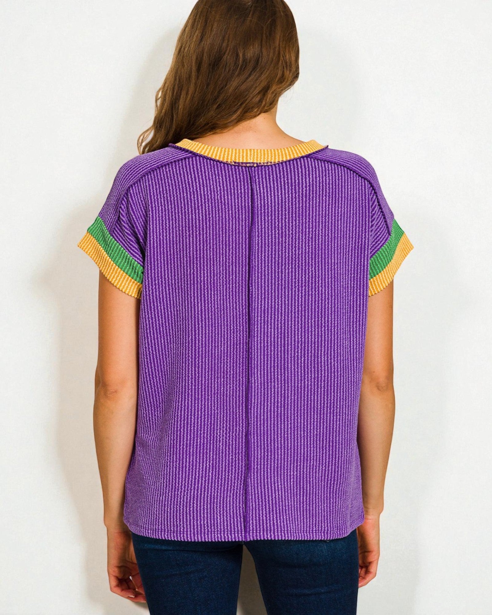 Purple ribbed sweater with yellow and green accents worn by a person on a white background