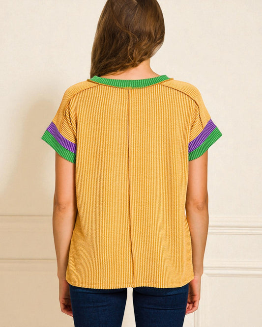 Yellow ribbed blouse with green and purple trim on a beige background
