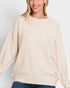 Woman wearing a beige sweater against a plain background
