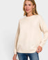 Woman wearing a beige sweater and blue jeans on a light gray background
