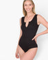 A woman modeling a black sleeveless one-piece bodysuit with a split neckline and keyhole cutout, photographed against a clean white studio background.