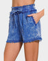 Blue denim shorts with frayed edges on a plain background