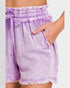 Purple denim shorts with frayed hem and white lace trim on a plain background