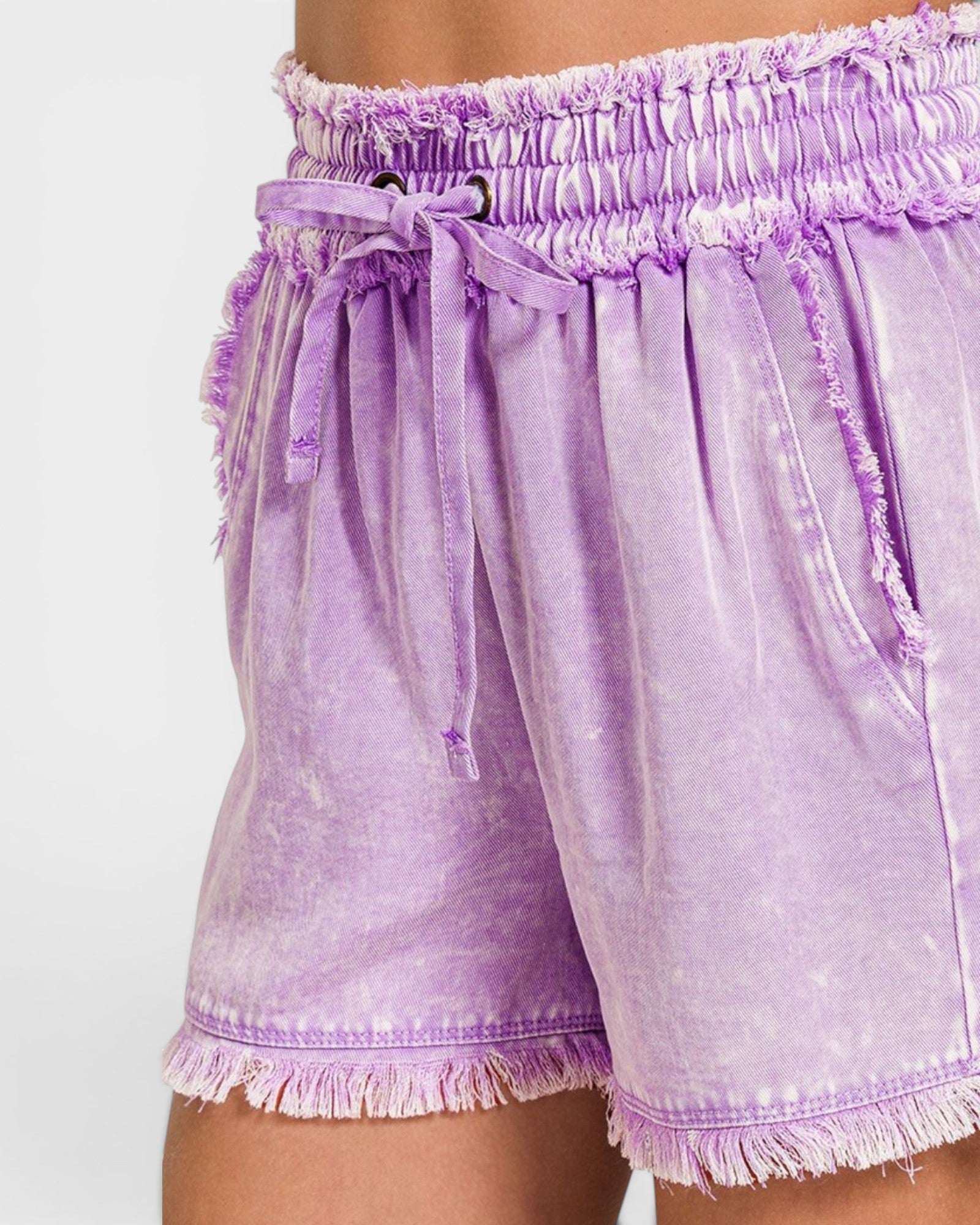 Purple tie-dye shorts with frayed edges on a white background