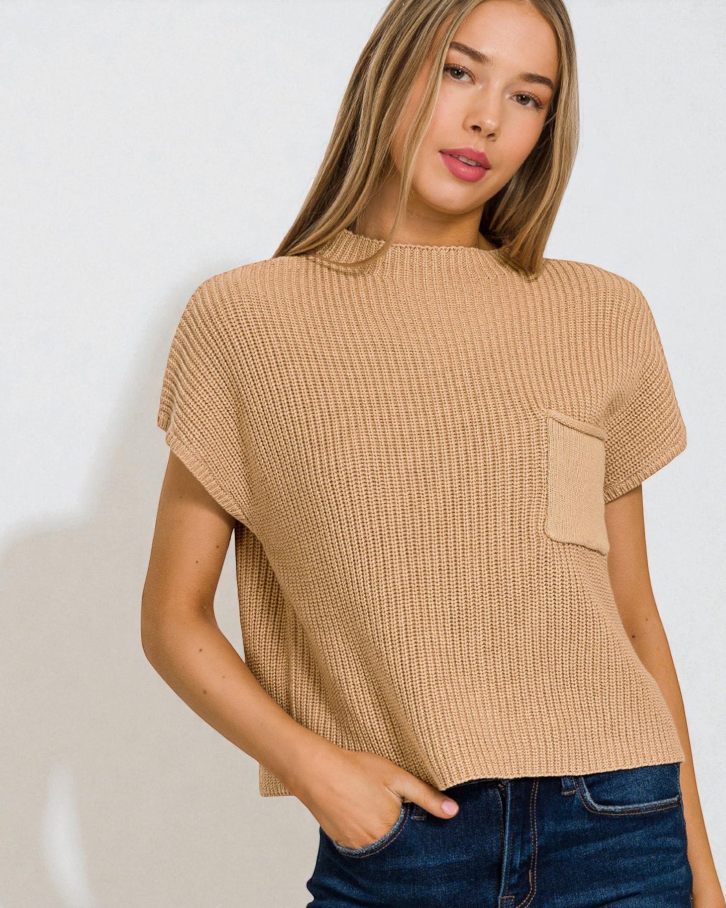 Woman wearing a beige textured top with a pocket against a white background