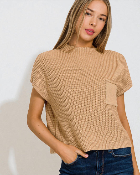 Woman wearing a beige textured top with a pocket against a white background