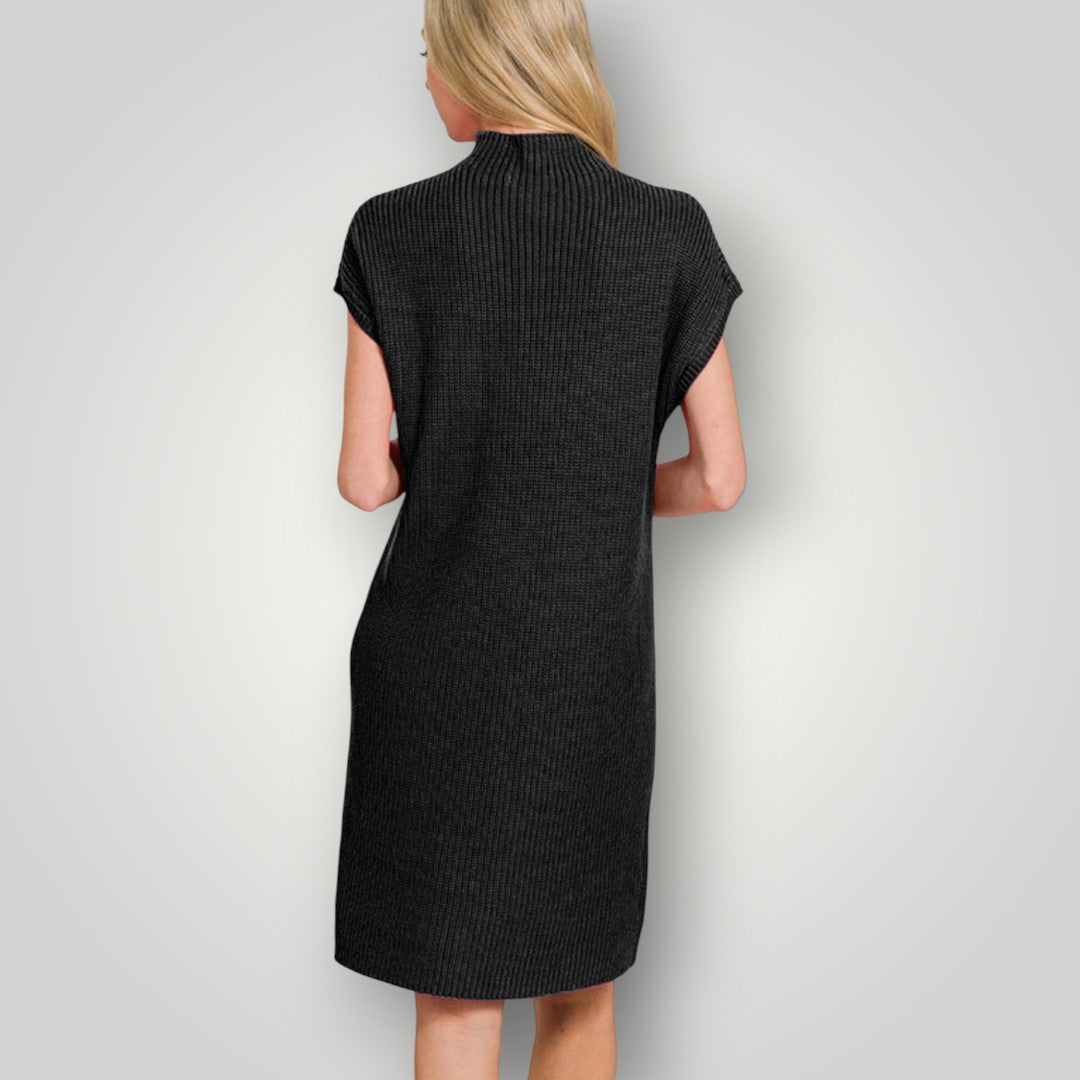 Woman wearing a black ribbed dress against a plain background