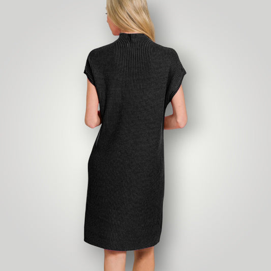 Woman wearing a black ribbed dress against a plain background