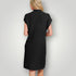 Woman wearing a black ribbed dress against a plain background