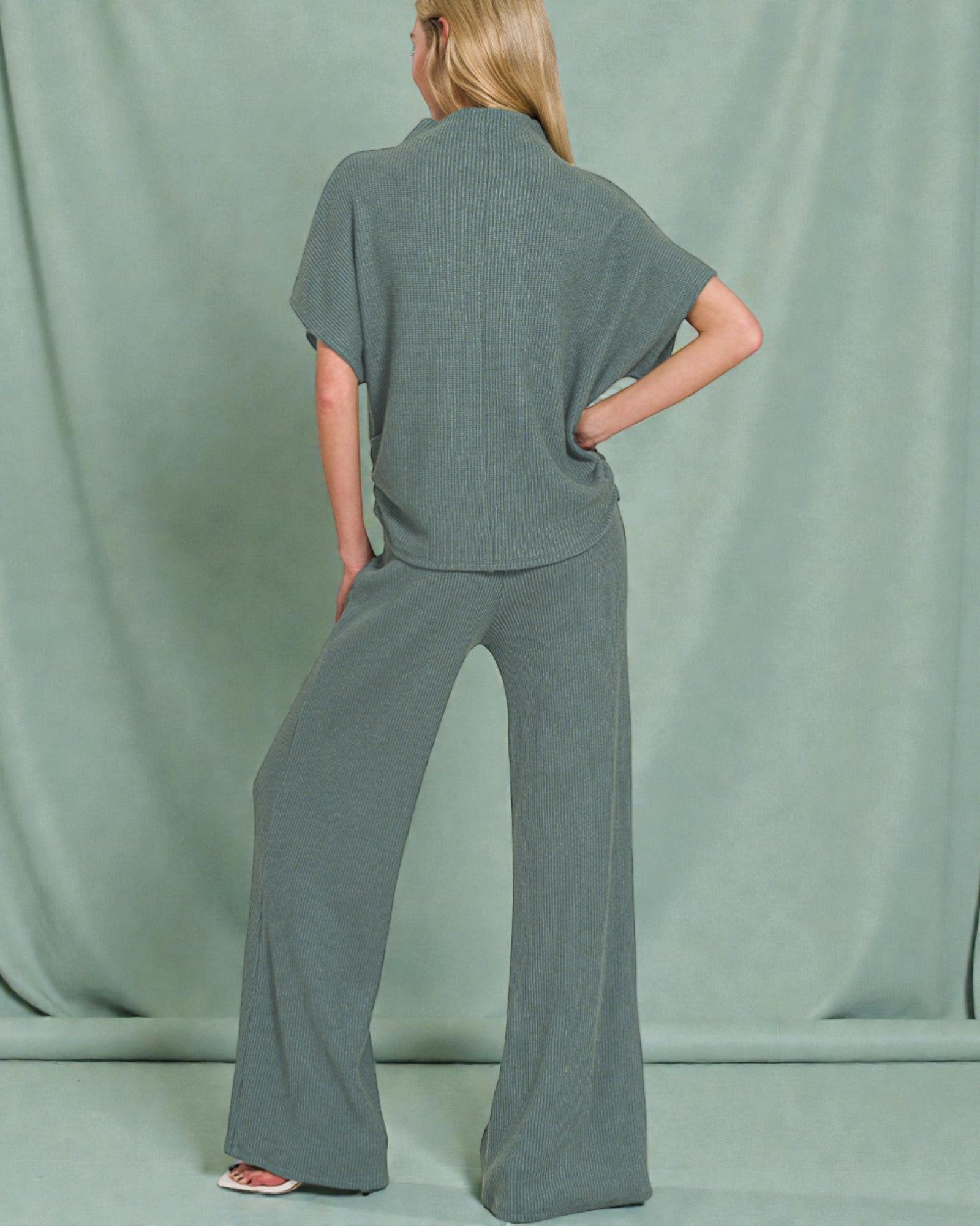 Person wearing a gray knit outfit against a plain background