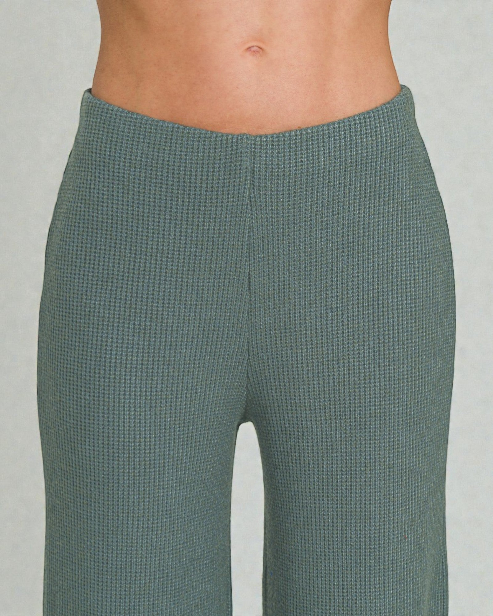 Green textured pants on a plain background