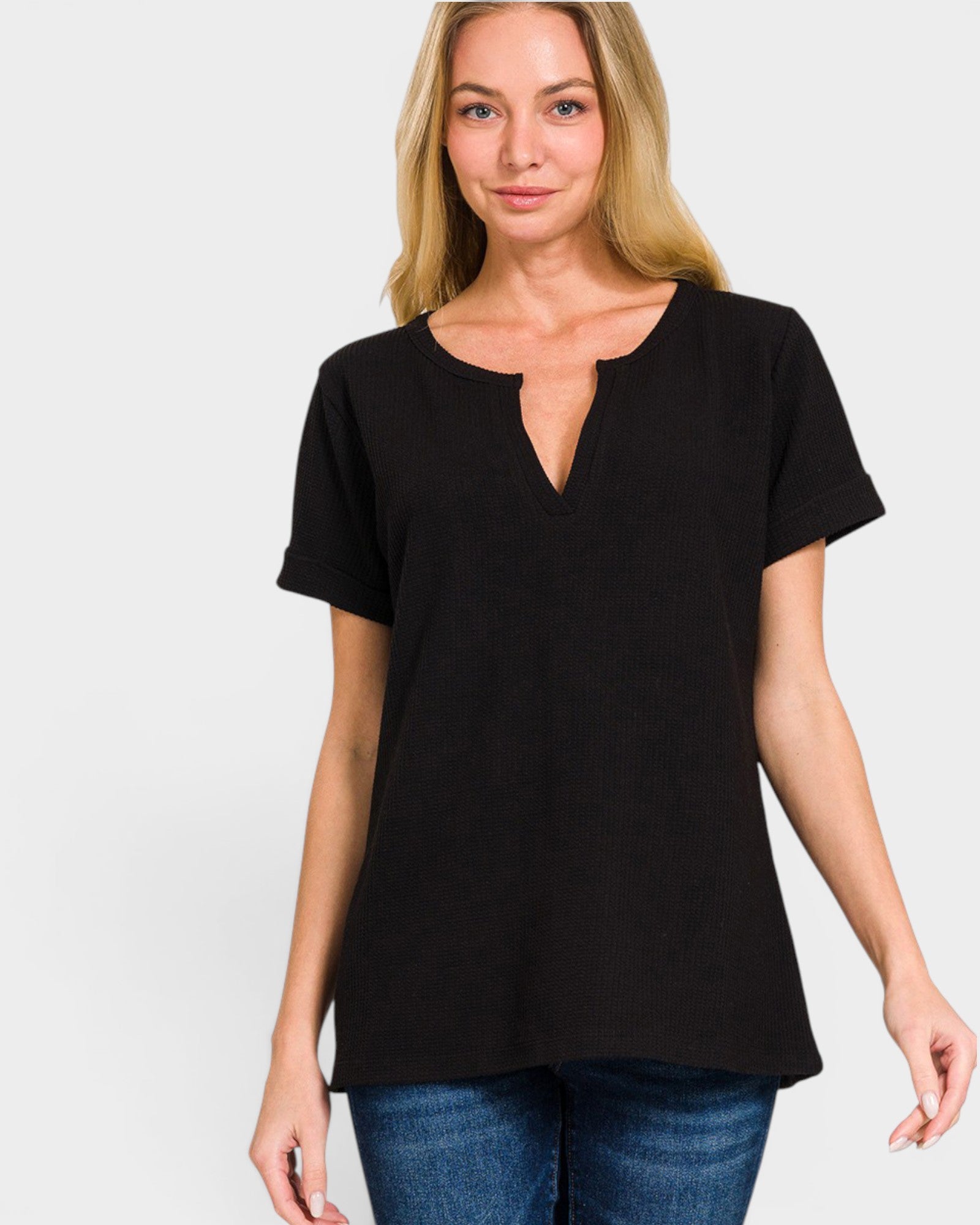 Woman wearing a black t-shirt with a deep neckline on a plain background