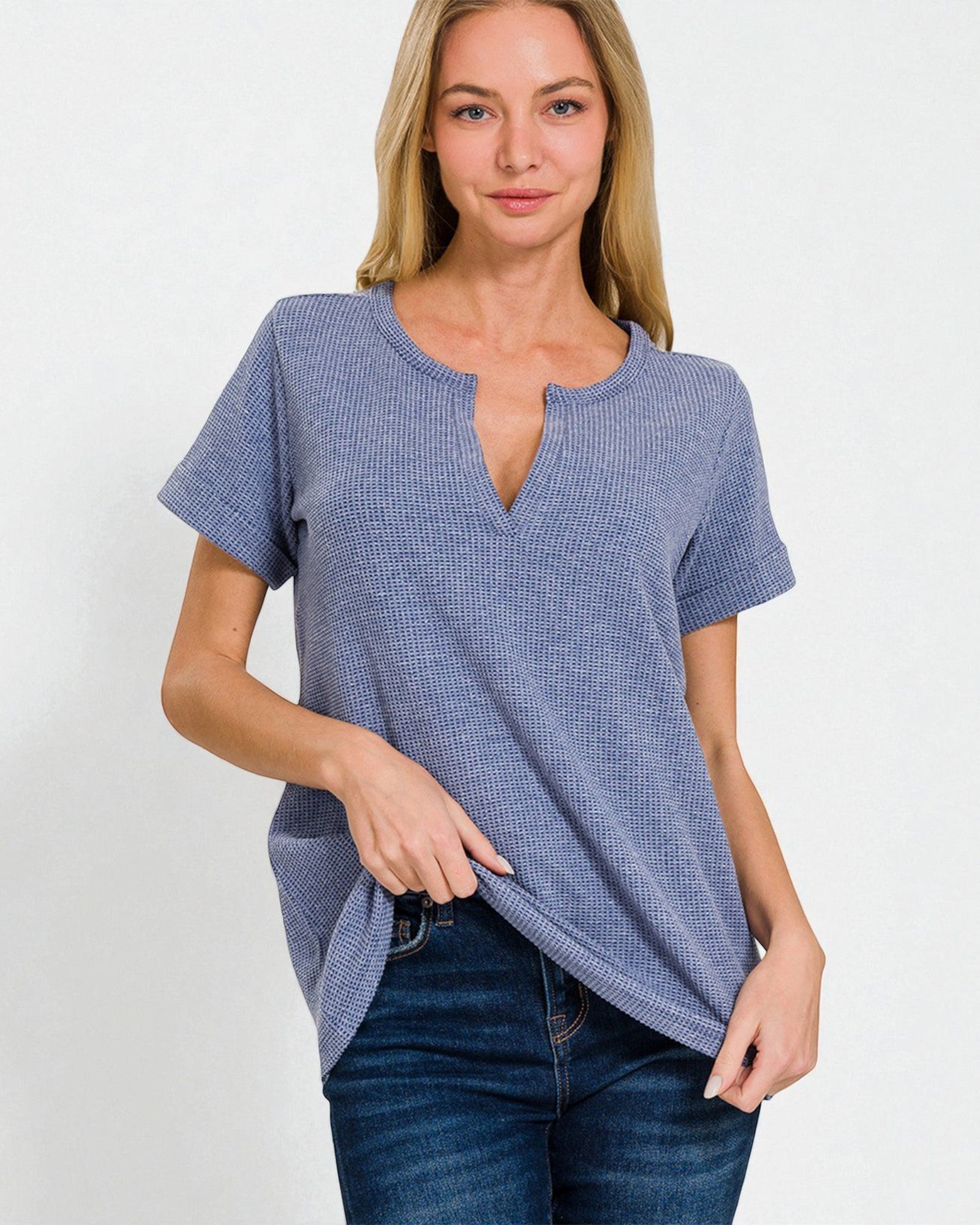 Woman wearing a blue textured top and jeans on a white background