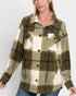 Person wearing a plaid shirt with green, brown, and white colors on a plain background
