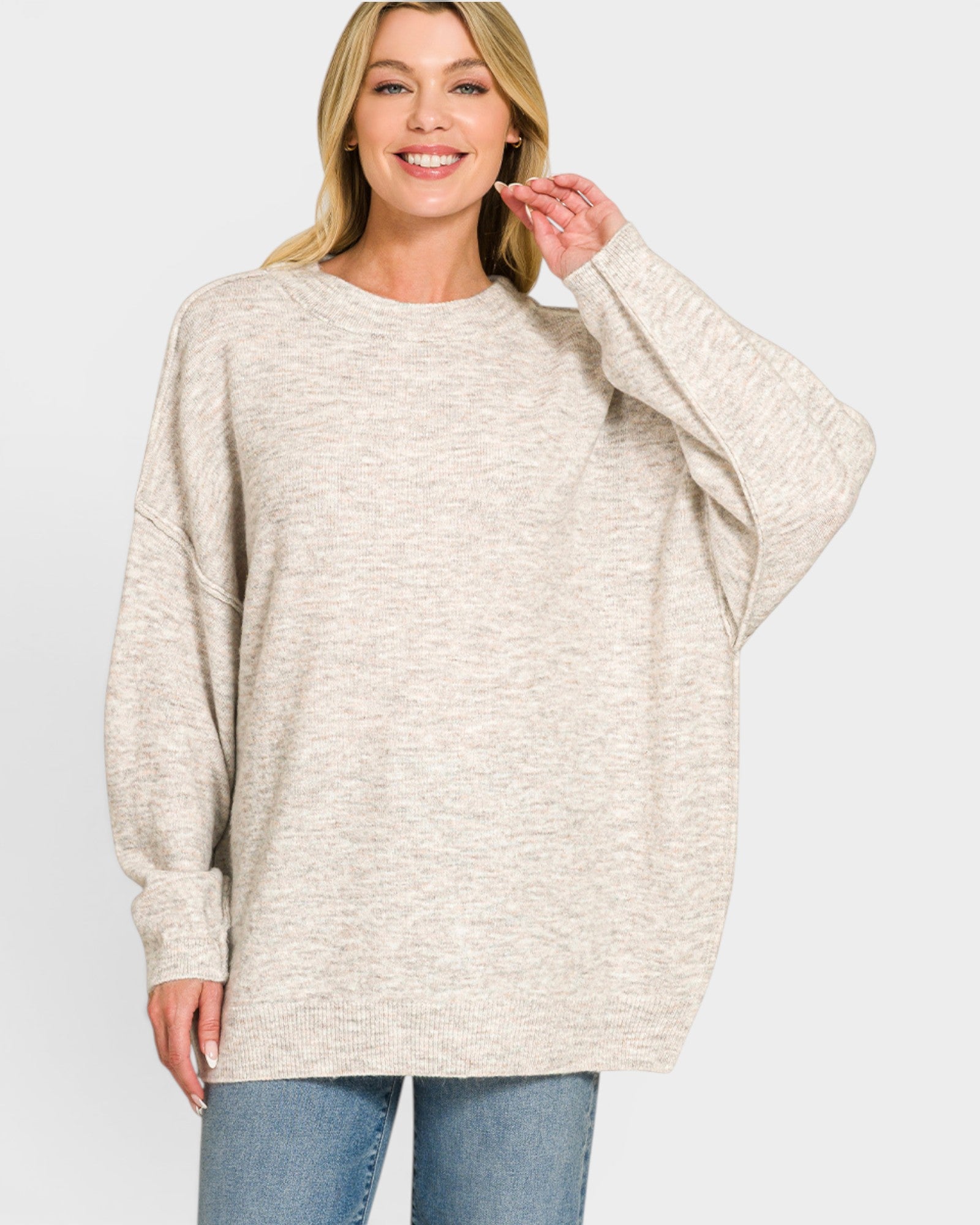 Woman wearing a beige sweater and blue jeans on a white background