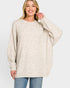 Woman wearing a beige sweater and blue jeans on a white background