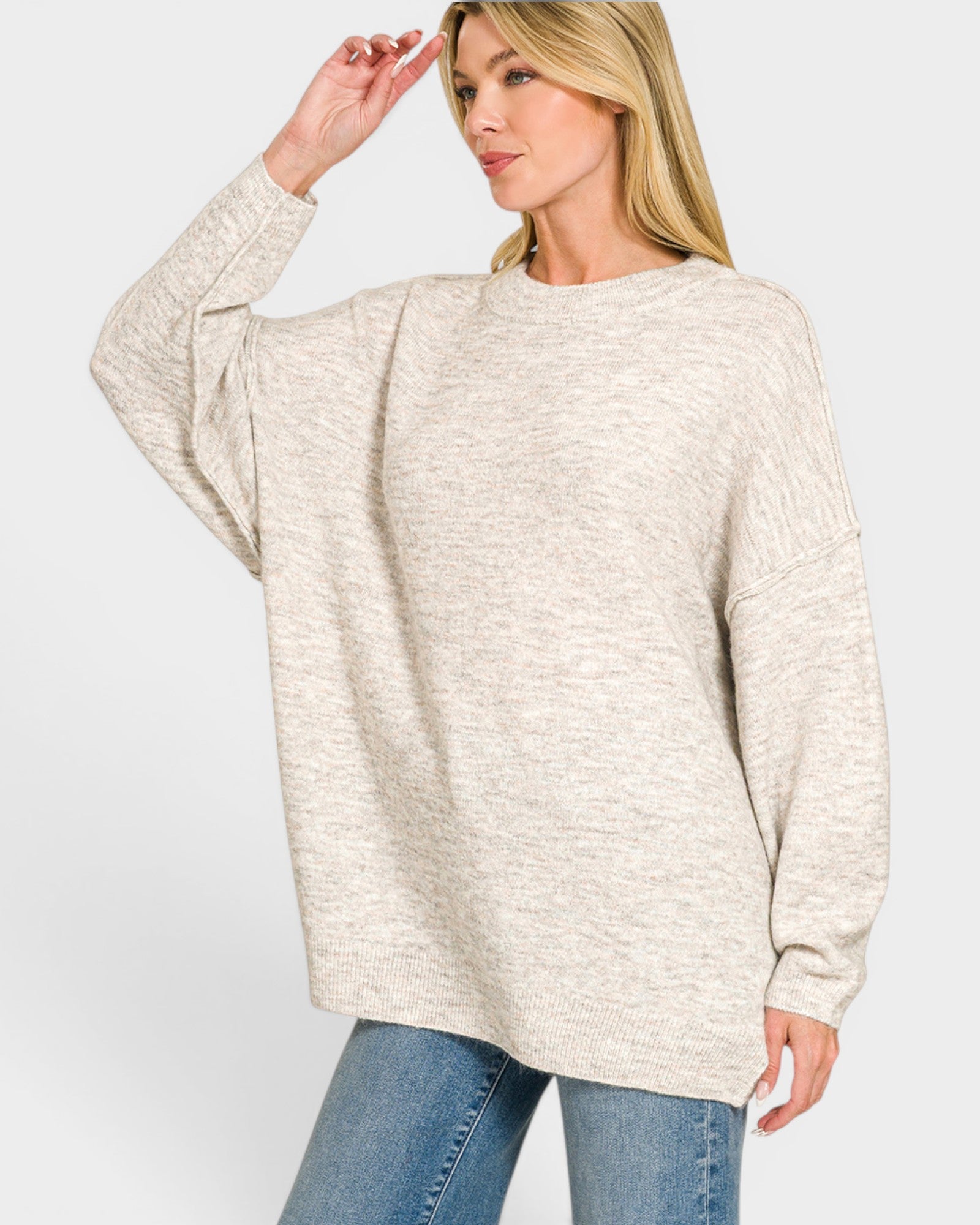 Woman wearing a beige sweater and blue jeans on a white background