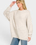 Woman wearing a beige sweater and blue jeans on a white background
