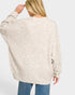 Person wearing a beige sweater and blue jeans on a white background