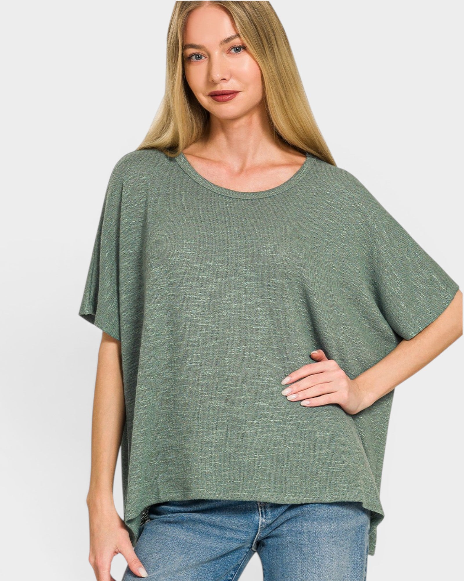 Woman wearing a green oversized shirt and blue jeans on a white background