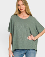 Woman wearing a green oversized shirt and blue jeans on a white background