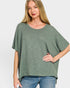 Woman wearing a green oversized shirt and blue jeans on a white background