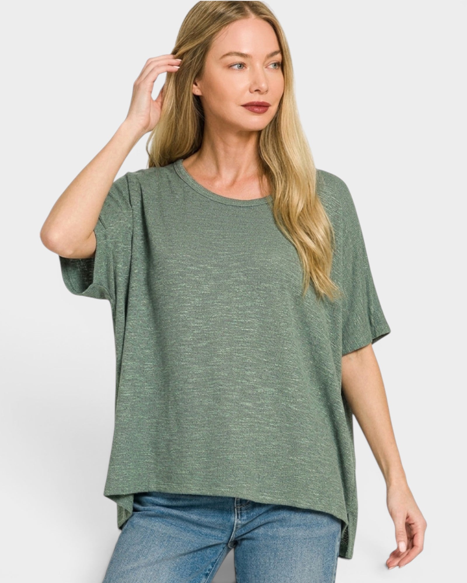 Woman wearing a green oversized t-shirt and blue jeans on a white background