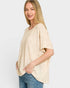 Woman wearing a beige oversized sweater and blue jeans on a white background