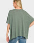 Woman wearing a green oversized t-shirt and blue jeans on a light gray background