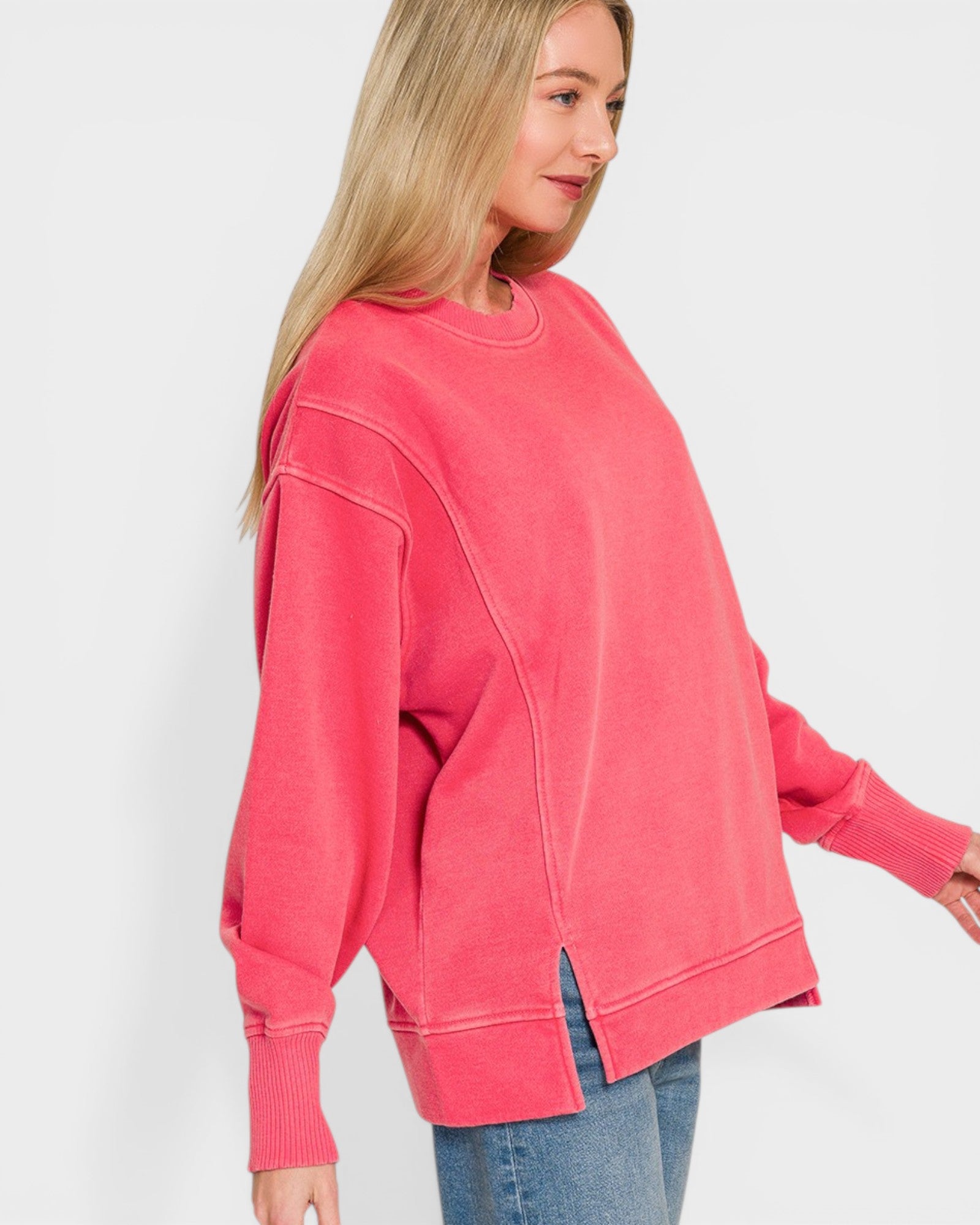 Woman wearing a pink oversized sweatshirt against a white background