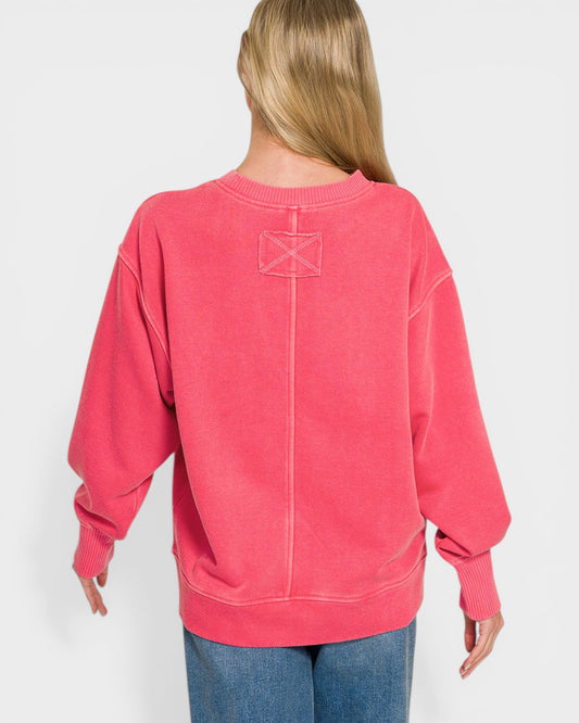 Person wearing a pink sweatshirt with a logo on the back against a white background