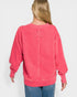 Person wearing a pink sweatshirt with a logo on the back against a white background