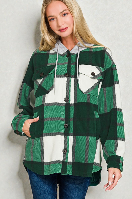 Woman wearing a green plaid shirt with a hood against a plain background